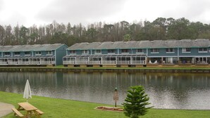 A lakeside hotel with multiple buildings, a dock, and a picnic table.