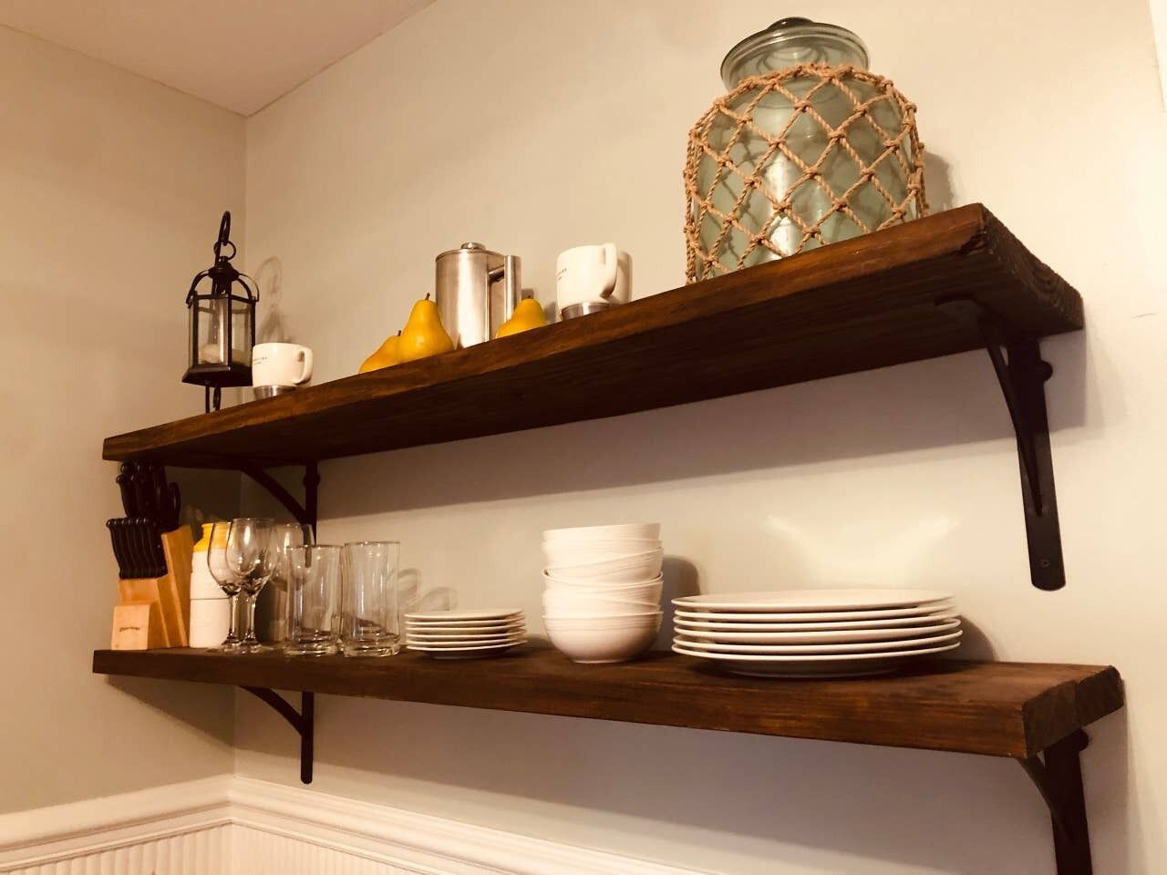 A wooden shelf with white plates, bowls, and a lantern.