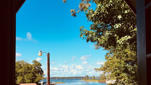 A wooden deck with two chairs, overlooking a lake with boats and a dock. - Privacy, fishing, pool--Just 10 mins to beach/base (Sneads Ferry)