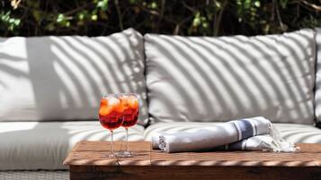 A wooden table with two glasses of red drink, a folded towel, and a sofa with striped cushions.