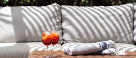 A wooden table with two glasses of red drink, a folded towel, and a sofa with striped cushions.