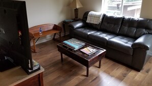 Una sala de estar con un sofá de cuero, una mesa de centro de madera y un televisor.
