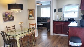 Un comedor con mesa y sillas de vidrio, una cocina con armarios de madera y una sala de estar con sofá y mesa de centro.