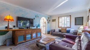 Ett vardagsrum med en TV, ett träskåp, en lädersoffa och ett soffbord.