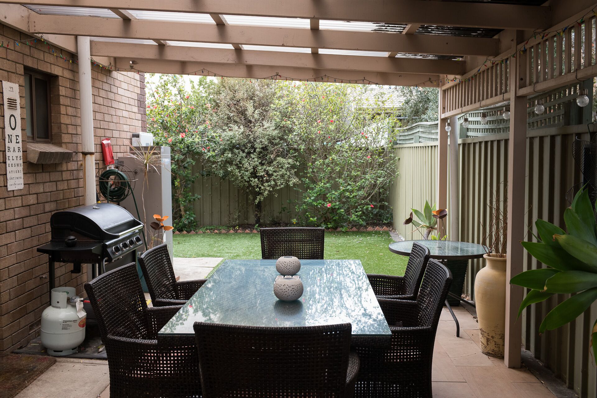 Eine Terrasse mit Tisch, Stühlen, einem Grill und einem Blumentopf.