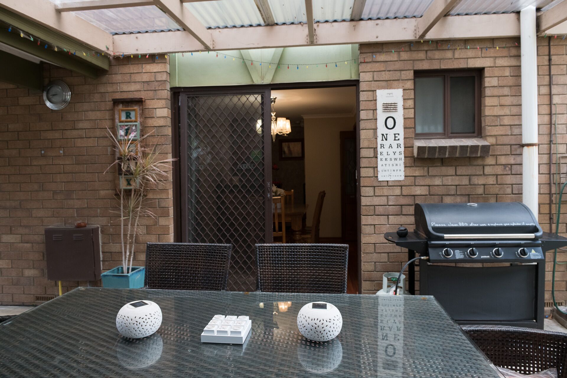 An outdoor patio with a grill, a table with two decorative items, and a sign with text.