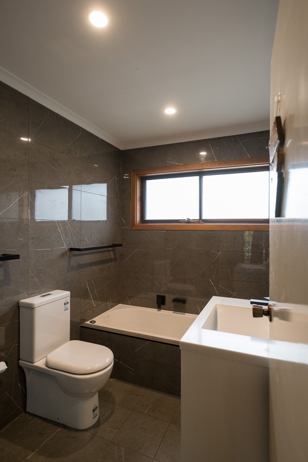 Een moderne badkamer met toilet, bad en wastafel.
