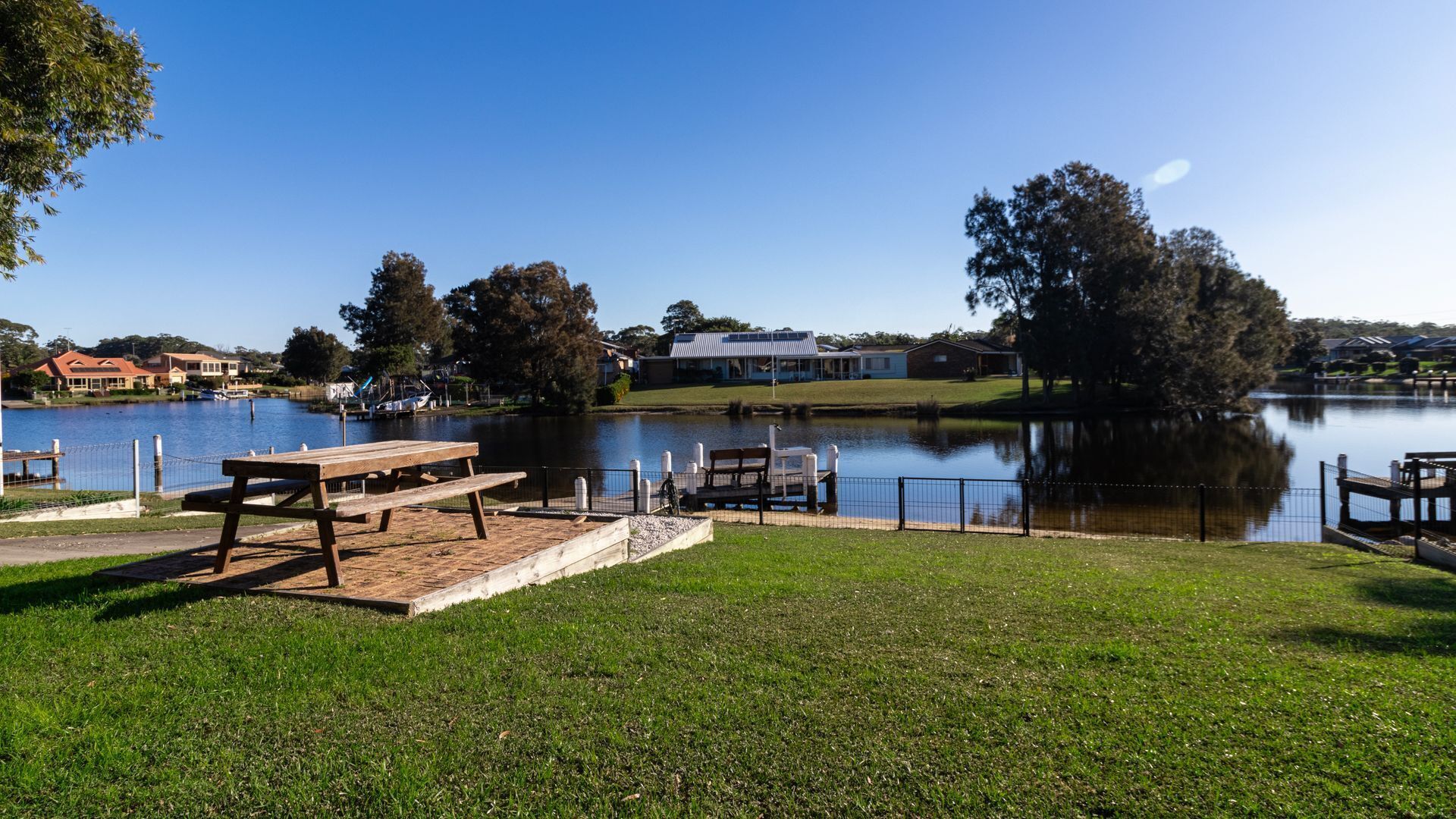A lakeside park with picnic tables and a dock.