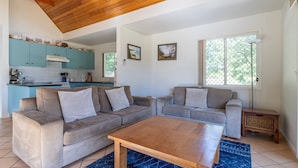 A living room with two sofas, a coffee table, and a kitchen in the background. - Sea Shell Chalet @ Berrara Chalet (Berrara)