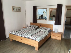 Une chambre à coucher avec un lit en bois, une table de chevet, un miroir et une armoire.