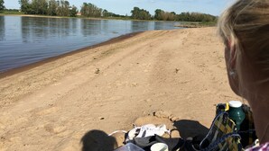 A sandy beach with a calm body of water, trees in the background, and a person with belongings on the sand. - Quiet large apartment between Nemitzer Heide and Elbtalaue (Trebel)