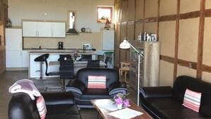 A modern living room with black leather sofas, a wooden coffee table, and a kitchen in the background. - Quiet large apartment between Nemitzer Heide and Elbtalaue (Trebel)