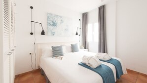 A hotel room with a large bed, two bedside tables, a ceiling fan, a wall-mounted lamp, and a window with curtains. - Ocean/volcano views, terrace, wifi, concierge [B] (Icod de los Vinos)