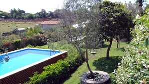 A swimming pool surrounded by lush greenery and a small garden area.
