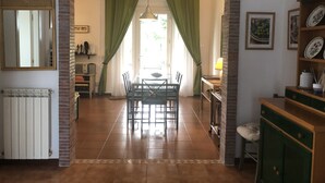 A dining area with a brick archway, a table with chairs, a radiator, and a shelf with plates.