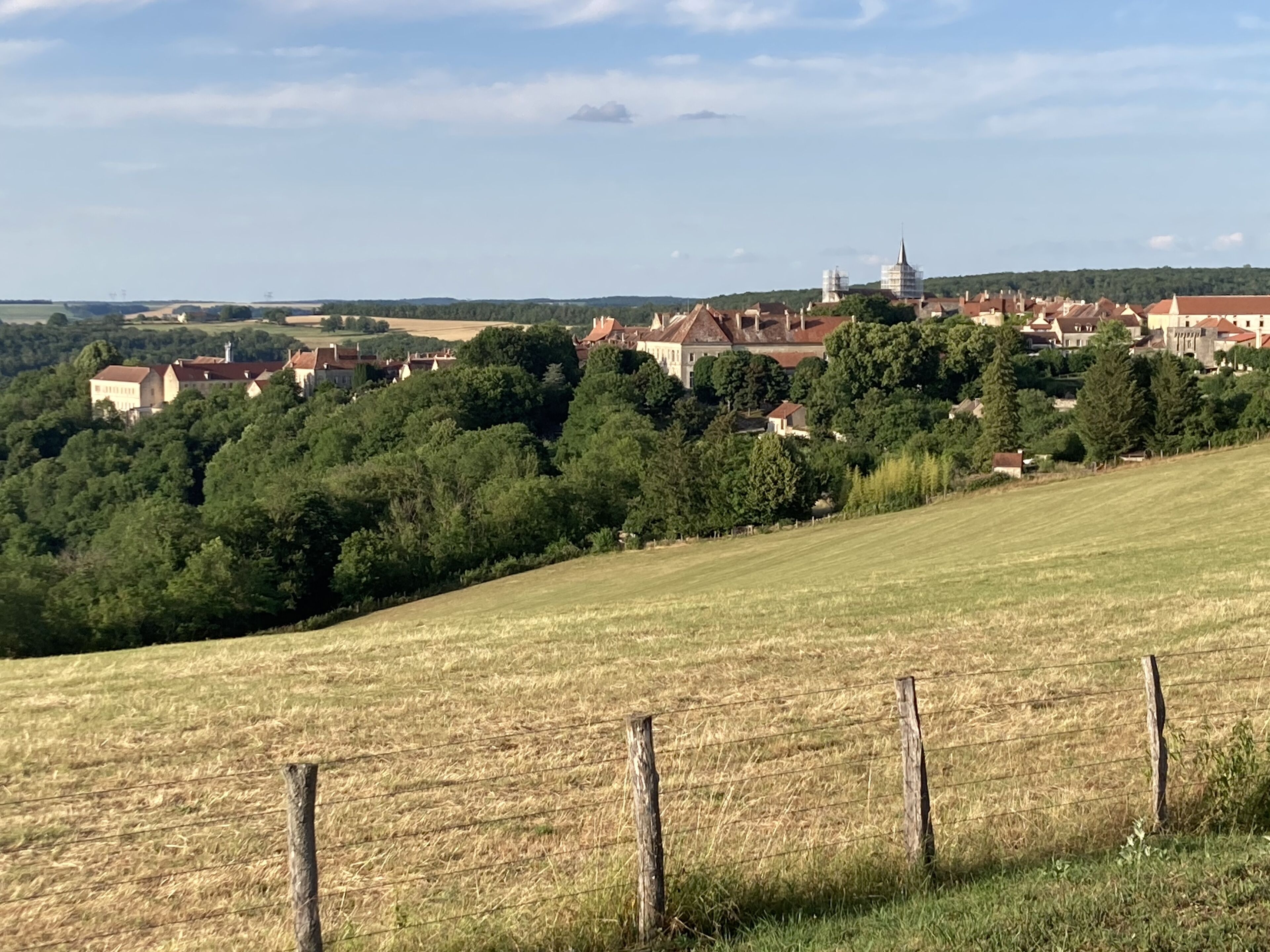A rural landscape with a hill, a church, and a row of houses.
