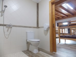 Compact bathroom with a toilet and shower unit, featuring a light-colored tile floor and white walls.