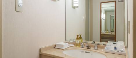 A hotel bathroom with a sink, mirror, and toiletries.