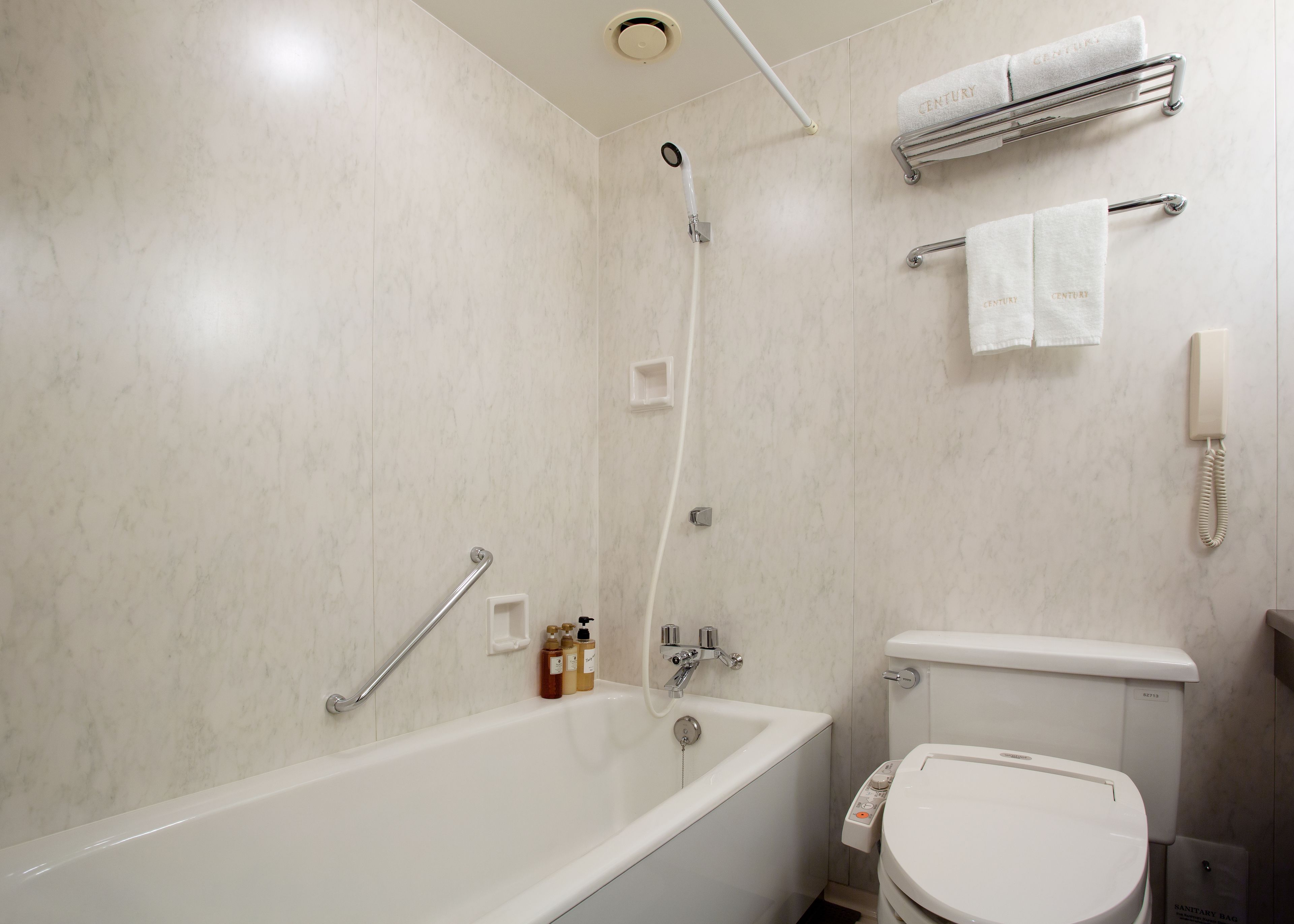 A bathroom with a bathtub, a toilet, a shower, and a towel rack with towels.