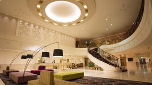 A spacious lobby with a central staircase, seating areas, and a reception desk. - Hotel Grand Hills Shizuoka (Shizuoka)