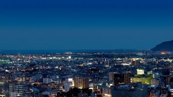 Uma paisagem urbana noturna com vista para a costa e uma montanha ao longe.