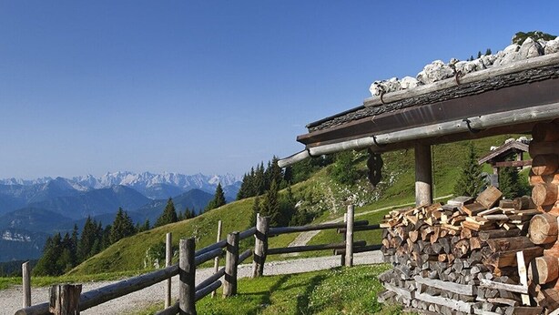 A wooden cabin with a stone foundation, surrounded by a wooden fence and a pile of firewood. - Hut magic meets 5* indulgence | Lenggries on the Isar (Lenggries)
