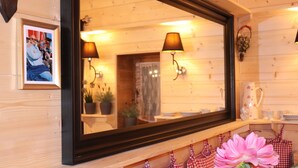 A wooden interior with a large mirror, wall-mounted lamps, and a framed photo. - Hut magic meets 5* indulgence | Lenggries on the Isar (Lenggries)