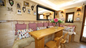 A wooden interior with a long table, chairs, and a bench with checkered cushions. - Hut magic meets 5* indulgence | Lenggries on the Isar (Lenggries)