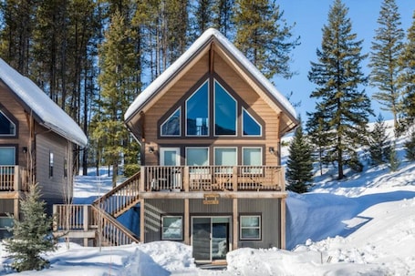 A two-story lodge with a balcony and a ski lift chair.
