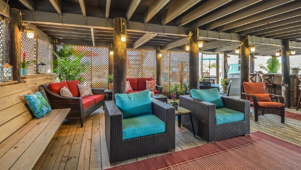 Un área de estar al aire libre con mobiliario de mimbre y una terraza de madera.