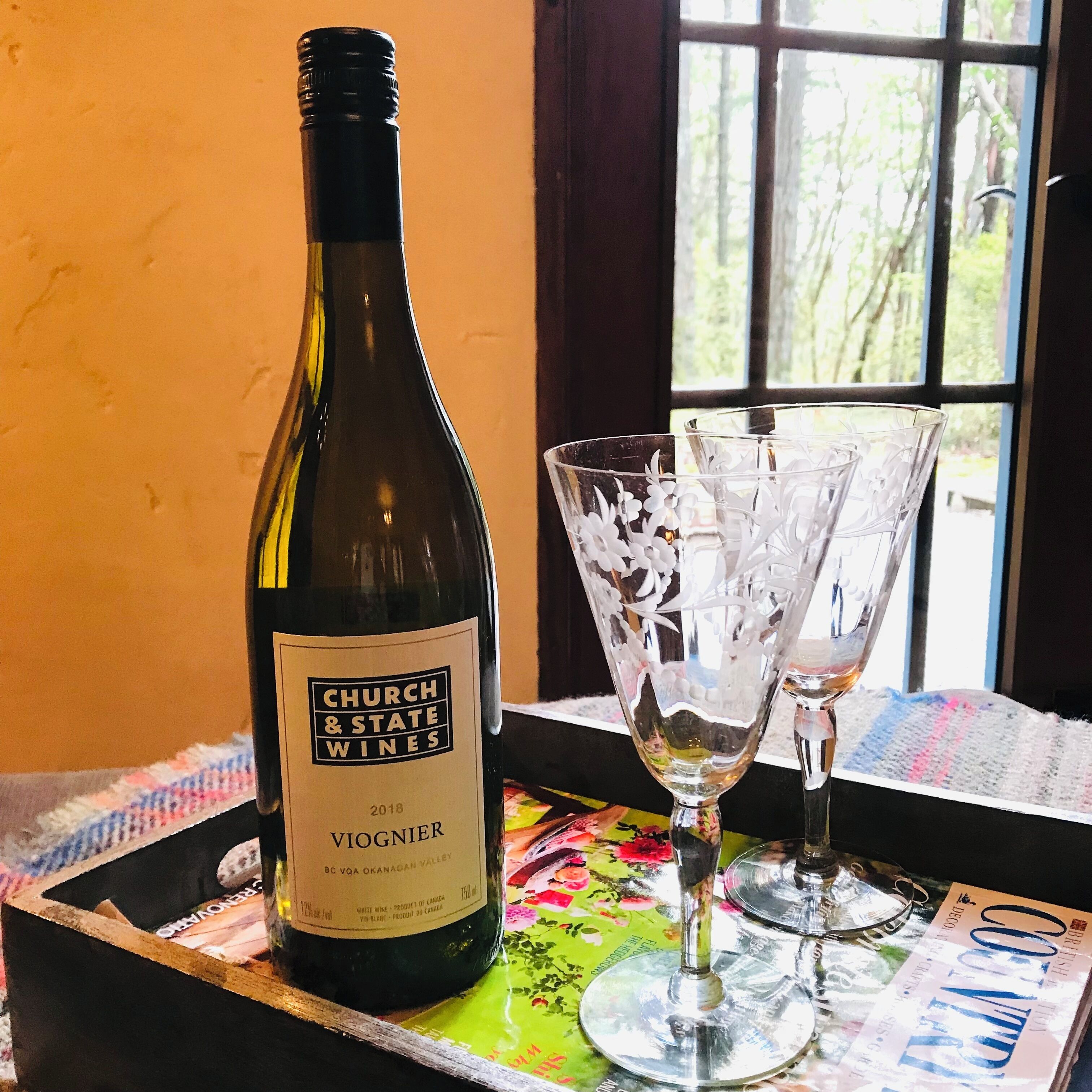 Una botella de vino Viognier Church & State Wines sobre una bandeja con dos copas de vino.