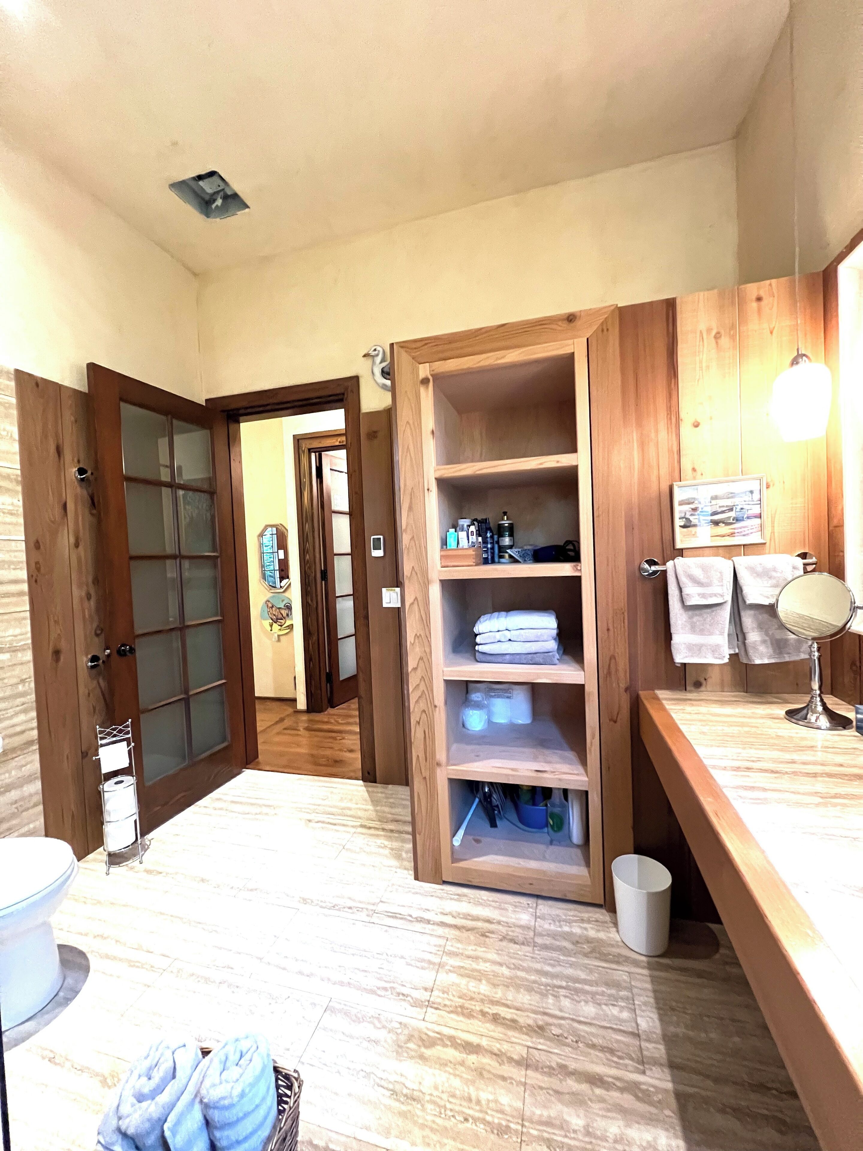 A bathroom with wooden shelving, a sink, and a mirror.
