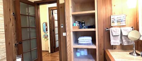 A bathroom with wooden shelving, a sink, and a mirror.
