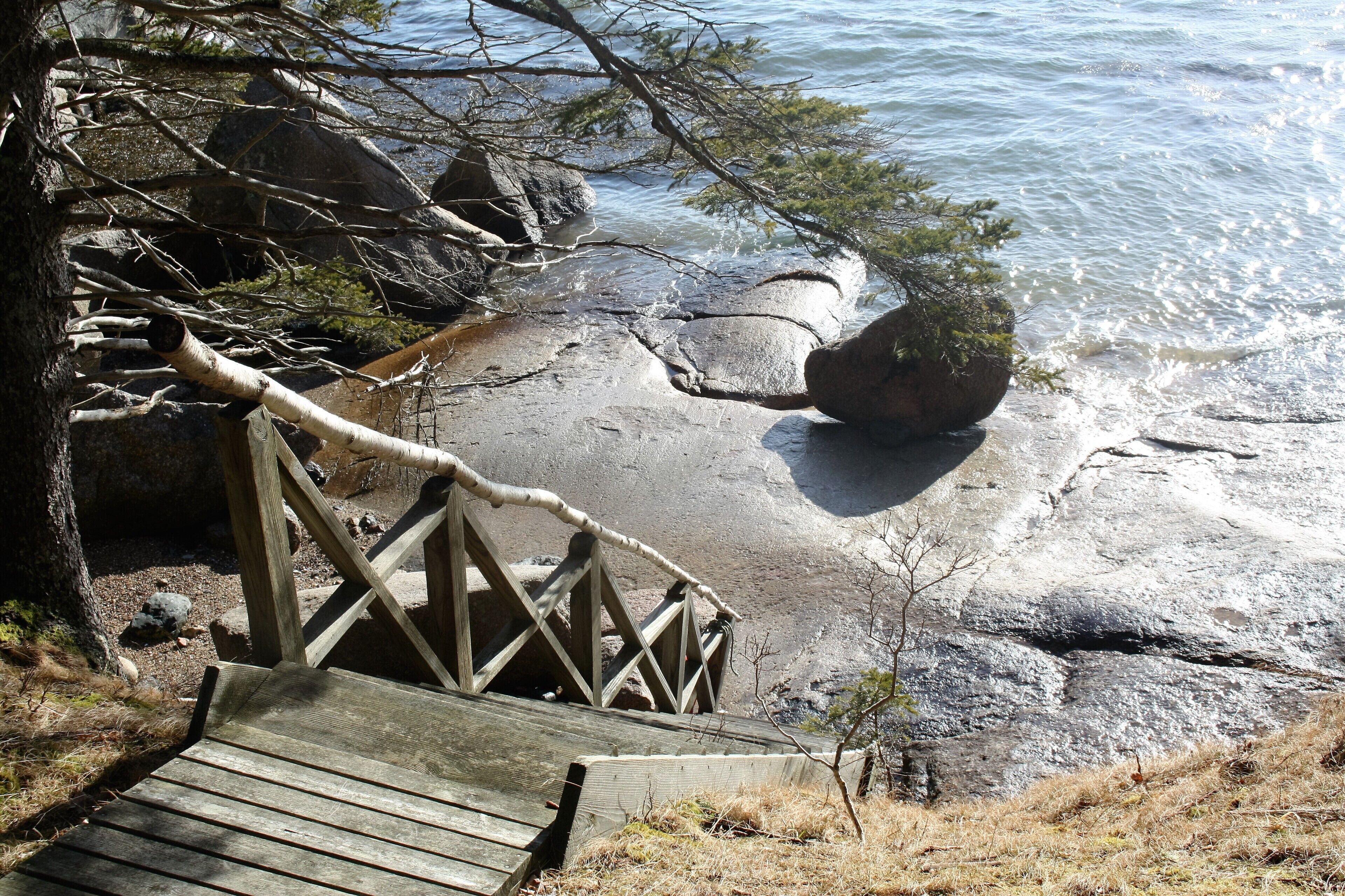 A wooden staircase leading to a rocky shoreline with clear water.