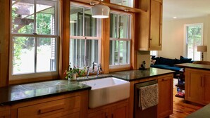 Una cocina con armarios de madera, un ventanal grande y un lavamanos.