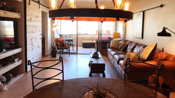 A cozy living room with a wooden coffee table, a sofa, and a TV. There is a dining area with chairs and a table. - Best Pool in the Area!- Walk to Everything Old Town! -2 Private Master Suites (Scottsdale)