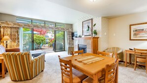 A spacious living area with a wooden dining table, striped armchairs, and a fireplace. - JL 305: Peaceful yet centrally located 2 bedroom, in the heart of Birch Bay. (Birch Bay)