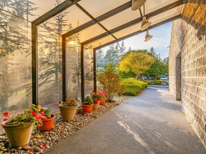 A covered walkway with potted plants and a stone wall.