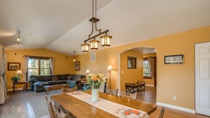 Uma sala de estar ampla com uma mesa de jantar de madeira, um sofá e um candelabro.