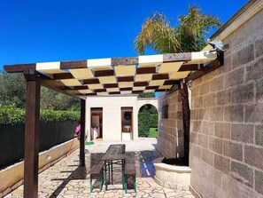 Eine Terrassengestaltung mit Pergola, Steinmauern und einer Steinsitzbank.