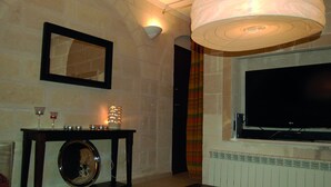 Ein Wohnzimmer mit Fernseher, Spiegel, Tisch mit Kerzen und Heizkörper.
