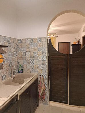 Ein Badezimmer mit einer Fliesenwand, einem Waschbecken und einer dunklen Holztür.
