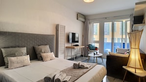 A hotel room with a bed, a TV, a desk, a chair, and a balcony with a view.