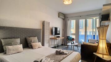 A hotel room with a bed, a TV, a desk, a chair, and a balcony with a view.