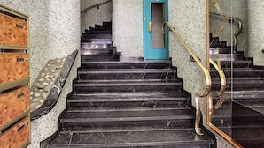 A staircase with black marble steps, a blue door, and a golden handrail.