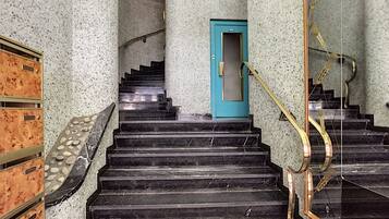 A staircase with black marble steps, a blue door, and a golden handrail.