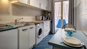 A compact kitchen with a washing machine, a microwave, and a sink.