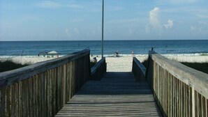 Un muelle de madera que conduce a una playa con una bandera en un asta.