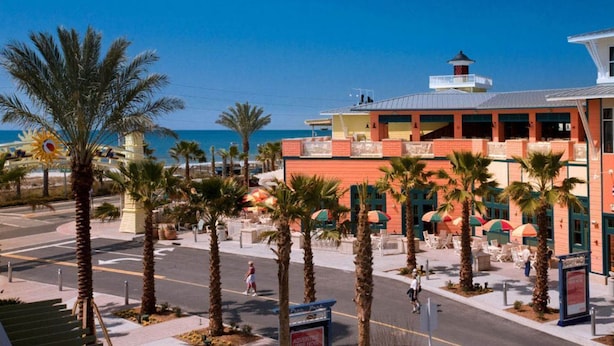 Un hotel frente al mar con una fachada llamativa de color rojo y amarillo, un balcón y vistas al océano.