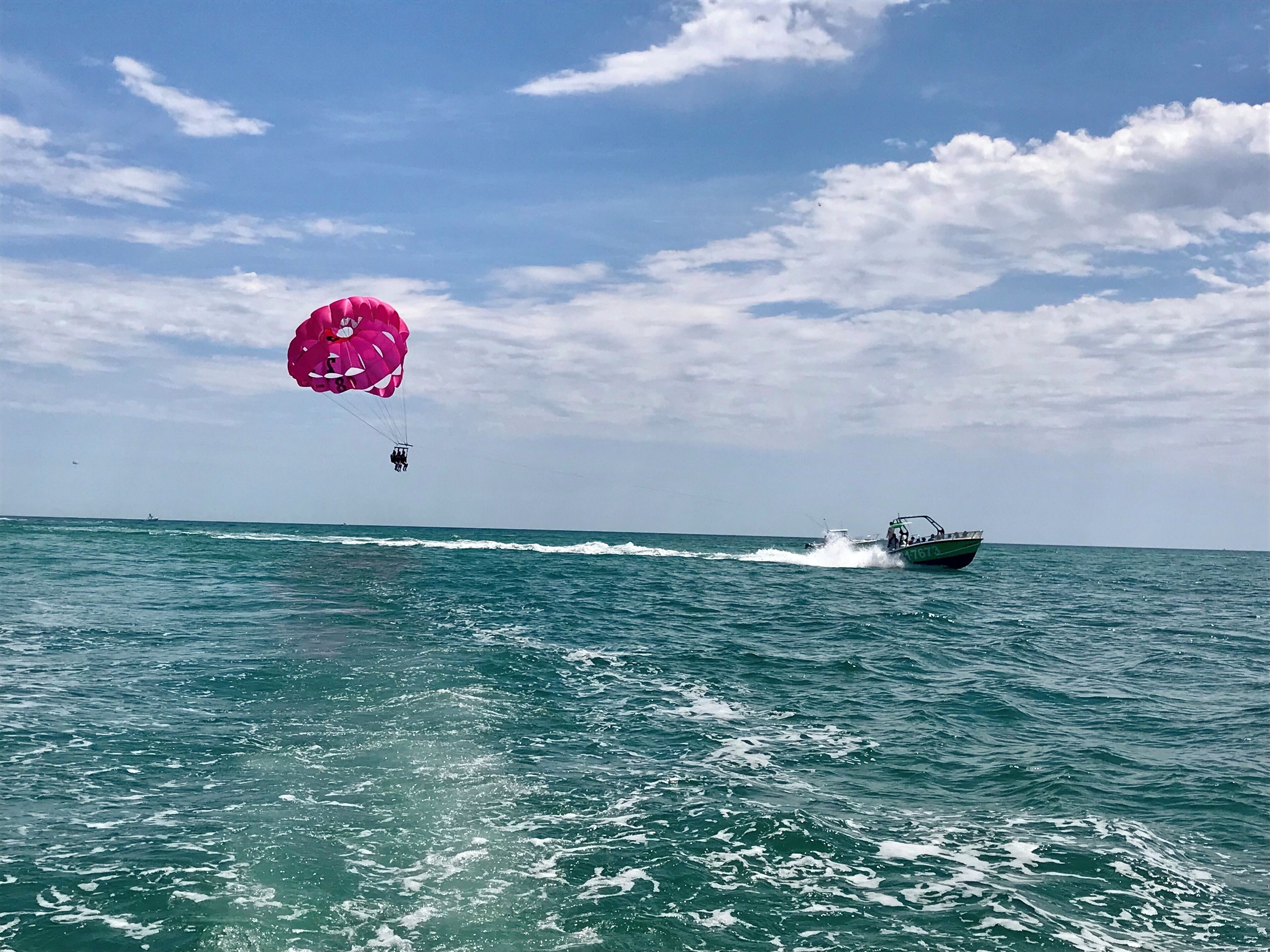 A parasailing activity over a body of water with a boat in the background.